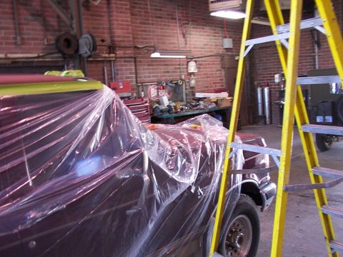 1988 Ford C-350 (Centurion Conversions) - Vehicle covered in plastic sheeting inside a workshop, with a ladder to the right.