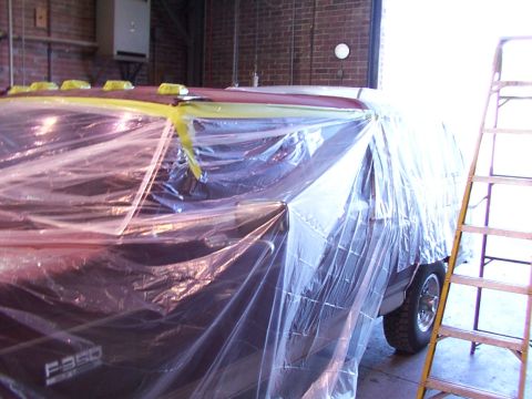 1988 Ford C-350 (Centurion Conversions) - A Ford F-350 truck is covered in plastic and tape, likely for painting, with a ladder nearby.