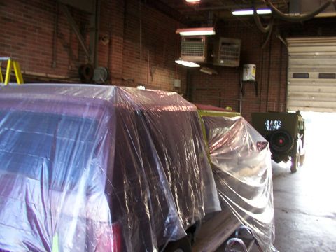 1988 Ford C-350 (Centurion Conversions) - Multiple vehicles are covered in plastic sheeting in a garage setting, awaiting work.