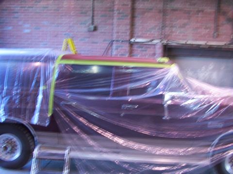 1988 Ford C-350 (Centurion Conversions) - A vehicle is covered in plastic and tape, ready for paintwork in an indoor setting.