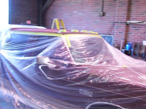 1988 Ford C-350 (Centurion Conversions) - A truck cab is covered in plastic sheeting, likely for painting or protection, protection, with a ladder in the background.