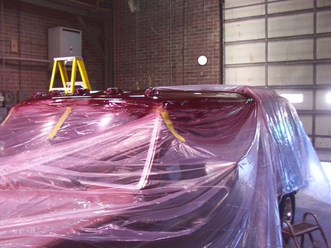 1988 Ford C-350 (Centurion Conversions) - A vehicle's roof is being painted red and is covered in plastic sheeting inside a garage.