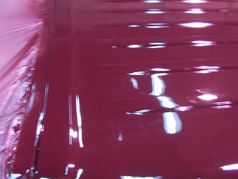 1988 Ford C-350 (Centurion Conversions) - The photo shows a close-up of a glossy, dark red painted surface with horizontal reflections.