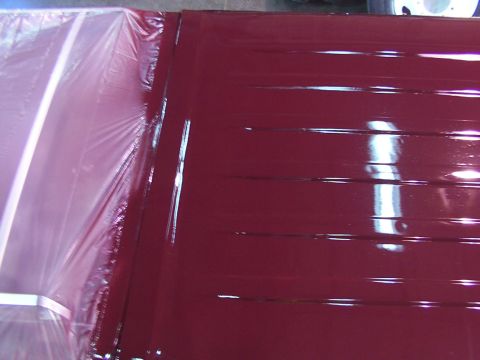 1988 Ford C-350 (Centurion Conversions) - A close-up view of a red roof panel, partially covered by protective plastic sheeting, showing horizontal ridges.