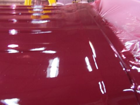 1988 Ford C-350 (Centurion Conversions) - The shiny red roof of a vehicle is visible, with reflections indicating overhead lighting.