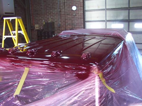 1988 Ford C-350 (Centurion Conversions) - The roof of a vehicle, covered in red paint and plastic sheeting, is visible in a workshop setting.
