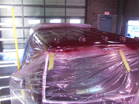 1988 Ford C-350 (Centurion Conversions) - A vehicle's roof is being painted red while covered in plastic sheeting inside a garage.