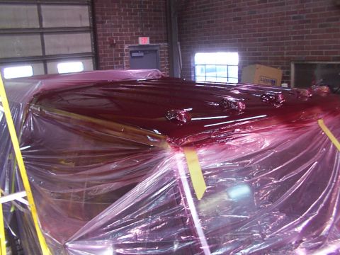 1988 Ford C-350 (Centurion Conversions) - A vehicle's roof is covered in plastic sheeting and a dark red liquid, possibly during a repair or cleaning process.