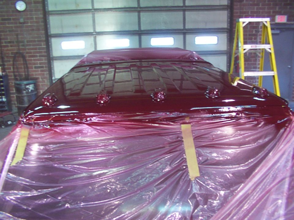 Red roof with chrome trim and lights, covered in plastic sheeting
