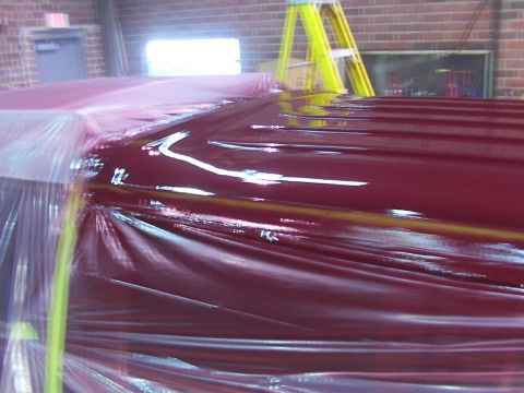 1988 Ford C-350 (Centurion Conversions) - A vehicle's roof, covered in protective plastic, displays a deep maroon color with visible horizontal lines.