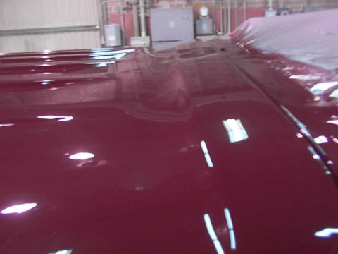 1988 Ford C-350 (Centurion Conversions) - The glossy maroon paint on the hood of a vehicle shows reflections of the surrounding environment.