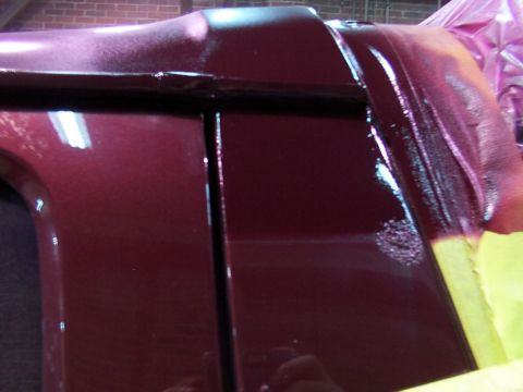 1988 Ford C-350 (Centurion Conversions) - Close-up of a maroon vehicle's door and roofline, showing dark trim and yellow masking tape, possibly during a paint job.