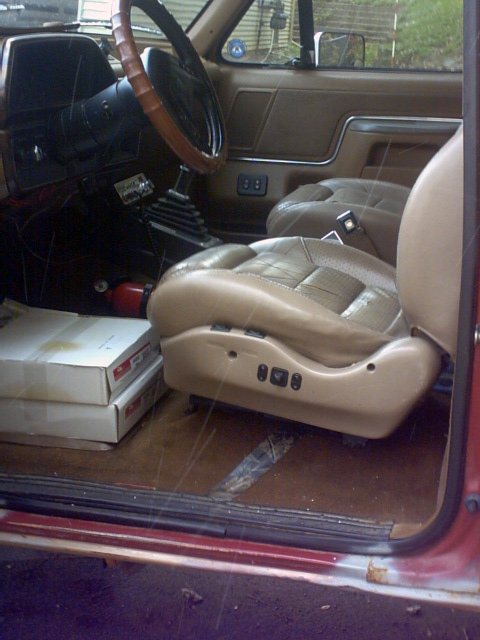1989 Ford Bronco - Interior view of a vehicle's front seats and dashboard, showing a manual transmission and floor storage.