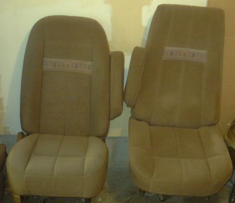 1989 Ford Bronco - Two tan fabric vehicle seats with armrests and a striped pattern on the backrests are shown.