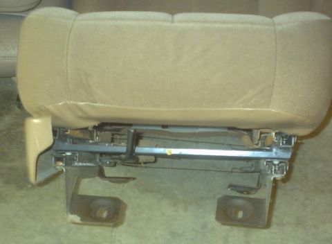 1989 Ford Bronco - Close-up view of a vehicle seat bottom and its underlying frame, showing mechanical components.