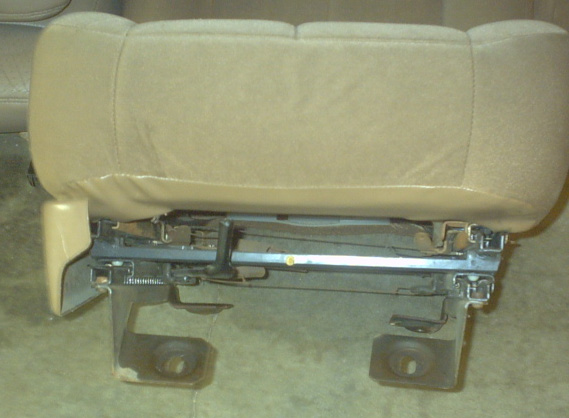 Tan seat bottom and metal frame with visible springs and adjustment mechanism