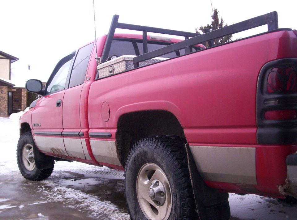 Red pickup truck with a toolbox in the bed and a rack over it. It has a two-tone paint job with tan lower panels
