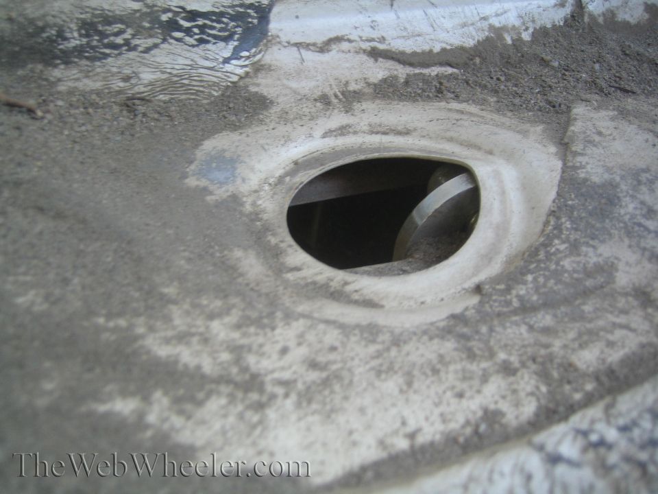 Close-up of a dirty, oval-shaped opening on a vehicle's undercarriage