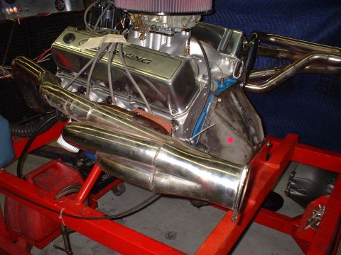 1969 Ford Mustang - A V8 engine is mounted on a red stand, chrome valve covers and custom exhaust headers.