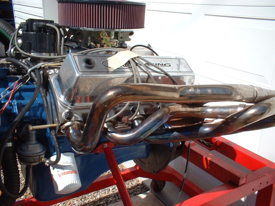 Chrome exhaust headers on a blue engine with a red air filter and a Motorcraft oil filter