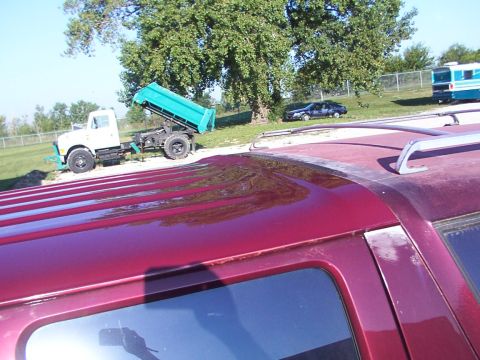 1988 Ford C-350 (Centurion Conversions) - The red SUV roof is in the foreground, with a dump truck and a dark sedan in the background.
