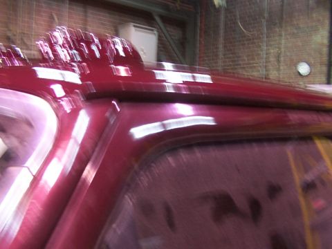 1988 Ford C-350 (Centurion Conversions) - Close-up of a red vehicle's roofline, showing a light bar. Image is blurry.