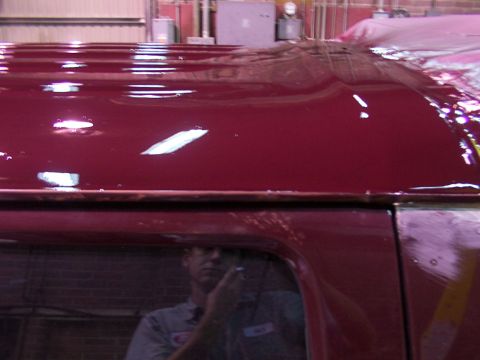 1988 Ford C-350 (Centurion Conversions) - The reflection shows a person in a work uniform holding a tool near the vehicle's roof.