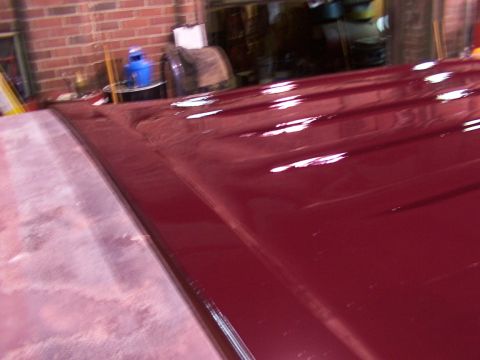 1988 Ford C-350 (Centurion Conversions) - Close-up view of a shiny red vehicle roof, showing its contours and reflections.
