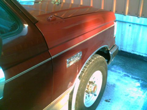 1988 Ford C-350 (Centurion Conversions) - Close-up of the fender and hood on a red 1988 Ford F-350 truck, showing chrome trim and the F-350 badge.