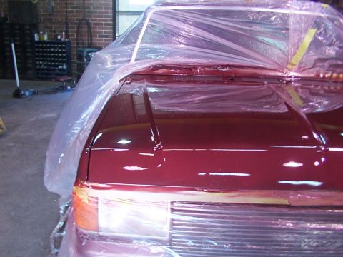 1988 Ford C-350 (Centurion Conversions) - A red pickup truck is covered in plastic sheeting, likely for painting, showing its front end.