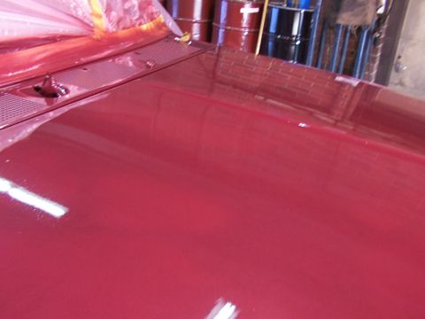 1988 Ford C-350 (Centurion Conversions) - Close-up of a shiny red vehicle hood and cowl, partially covered with protective plastic sheeting.