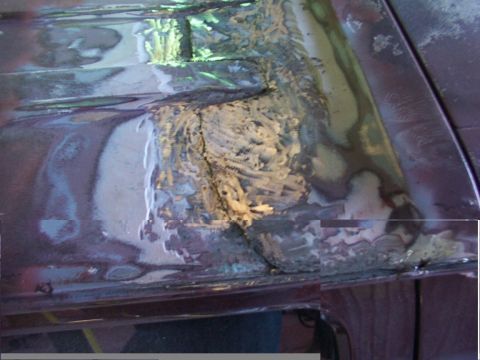 1988 Ford C-350 (Centurion Conversions) - Close-up of damaged vehicle bodywork, revealing rust and filler on the roof panel during repair.