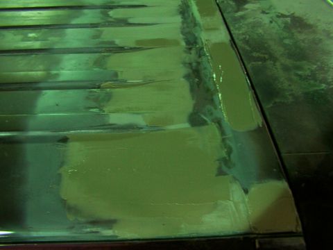 1988 Ford C-350 (Centurion Conversions) - Body filler is being applied to a ribbed vehicle roof panel during a repair process.