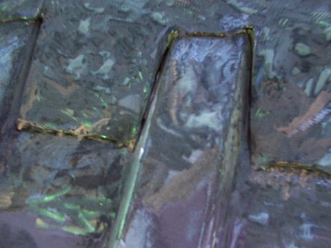 1988 Ford C-350 (Centurion Conversions) - Close-up of a textured, dark material with reflective highlights, possibly an interior car part.