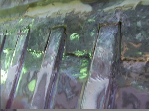 1988 Ford C-350 (Centurion Conversions) - Close-up view of ribbed metal paneling, showing reflections of the surroundings.