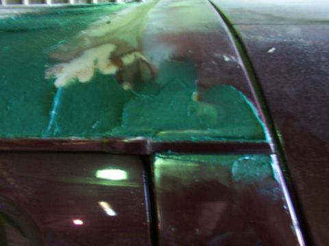 1988 Ford C-350 (Centurion Conversions) - Close-up view of damaged car roof bodywork showing green primer and peeling paint.
