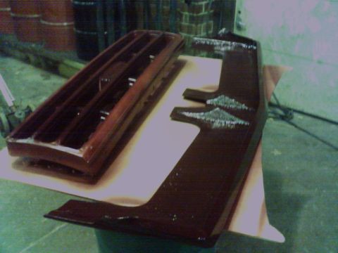 1988 Ford C-350 (Centurion Conversions) - Two automotive parts, a grille and a visor, are displayed on a table, likely awaiting installation or repair.