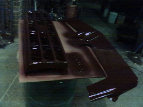 1988 Ford C-350 (Centurion Conversions) - Car grille and fender part, painted dark red, resting on cardboard in a workshop.