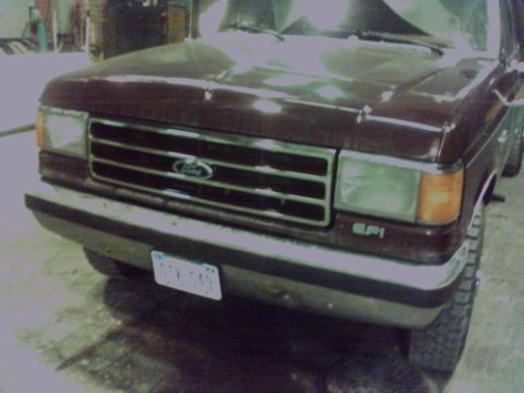 1988 Ford C-350 (Centurion Conversions) - The grille and headlights of a maroon Ford truck are visible, with a license plate in the front bumper.