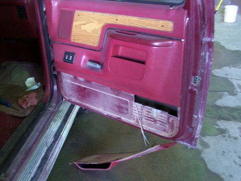 1988 Ford C-350 (Centurion Conversions) - Interior of a maroon vehicle door, showing wood trim and detached lower panel with exposed wiring.