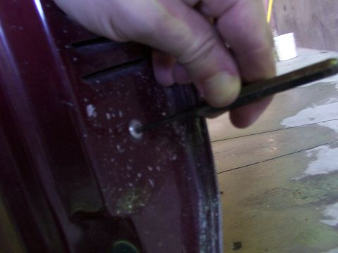 1988 Ford C-350 (Centurion Conversions) - Prying a small circular piece from a car door panel with a screwdriver.