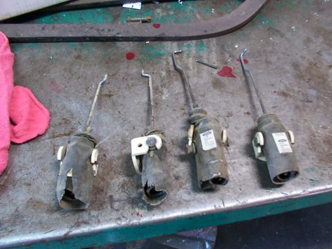 1988 Ford C-350 (Centurion Conversions) - Four Ford door lock actuators are laid out on a workbench, showing their mechanical components and some visible branding.