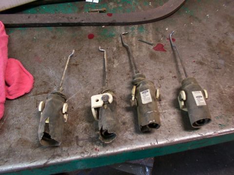 1988 Ford C-350 (Centurion Conversions) - Four Ford door lock actuators are shown on a metal workbench, some with visible Ford branding.