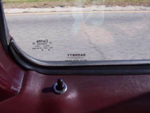 1988 Ford C-350 (Centurion Conversions) - Interior view of a vehicle's driver's door, showing the lock knob and window with manufacturer markings.