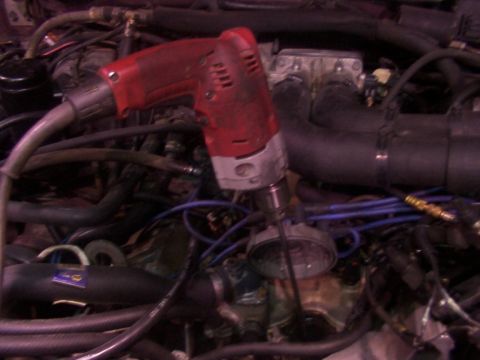 1988 Ford C-350 (Centurion Conversions) - A red drill is positioned over engine parts, amidst a tangle of hoses and electrical wiring.