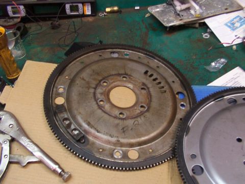 1988 Ford C-350 (Centurion Conversions) - Close-up of a flywheel and another transmission component on a workbench.