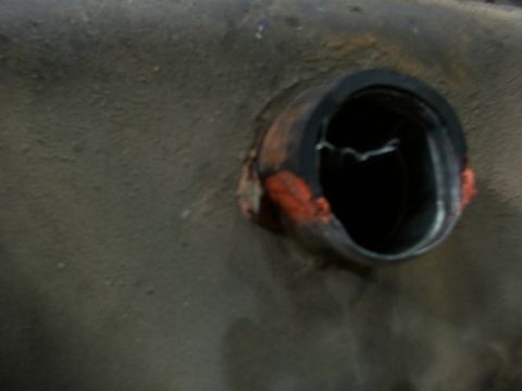1988 Ford C-350 (Centurion Conversions) - Close-up view of a damaged fuel filler neck on a vehicle's undercarriage.