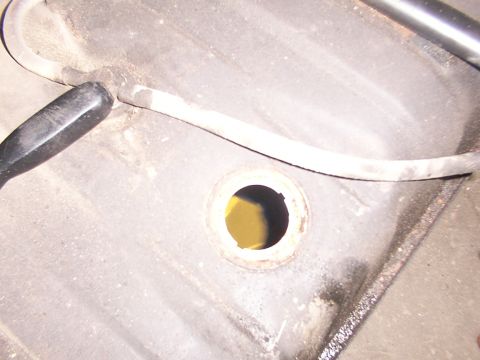 1988 Ford C-350 (Centurion Conversions) - Close-up view of a vehicle's fuel tank opening, showing a black hose connected to the top.