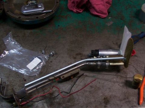 1988 Ford C-350 (Centurion Conversions) - A disassembled fuel pump assembly lies on a concrete floor next to a plastic bag and tools.