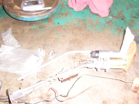 1988 Ford C-350 (Centurion Conversions) - A disassembled fuel pump assembly is laid out on a workbench, showing its various components and wiring.